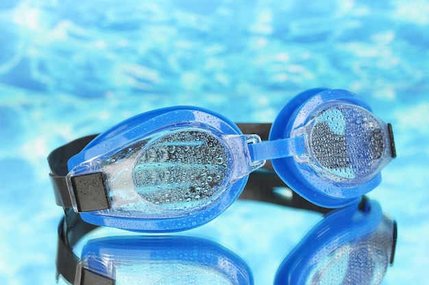 Óculos de natação azuis com gotas no fundo do mar azul