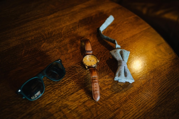 Óculos de relógio de gravata borboleta cinza masculino elegante para o noivo Acessórios de casamento em fundo marrom de madeira composição de ideia tradicional Acessórios para um empresário