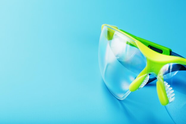 Óculos de segurança de policarbonato transparente sobre fundo azul.