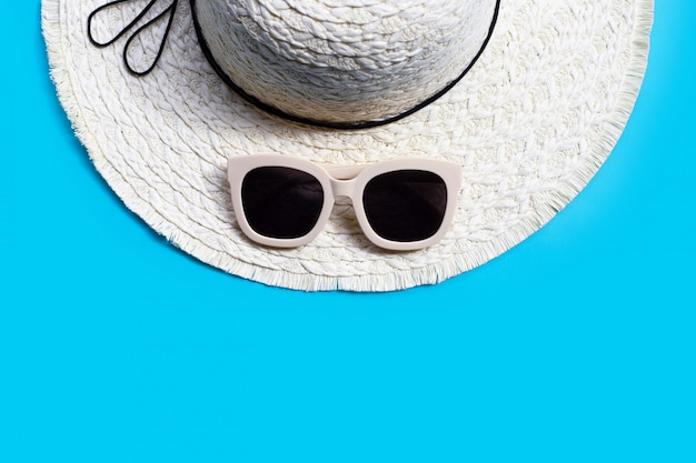 Óculos de sol com chapéu de verão em fundo azul. Aproveite o conceito de férias.