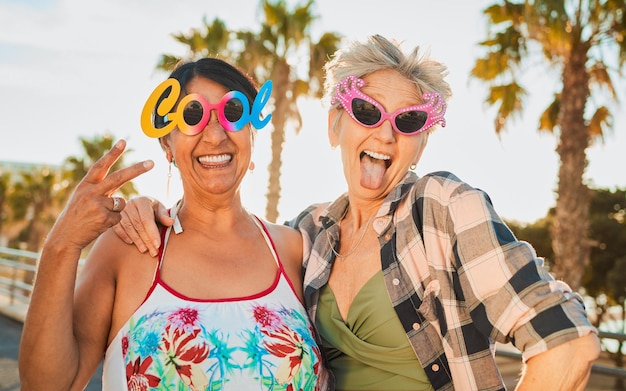 Óculos de sol divertidos de férias e mulheres idosas aposentadas em uma viagem de fim de semana de verão juntas Feliz liberdade e amigas idosas com óculos elegantes se divertindo durante uma aventura de férias