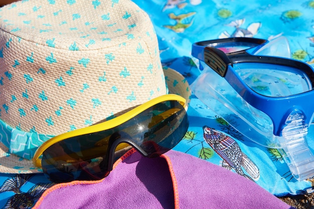 Óculos de sol e toalha de chapéu de máscara de natação na praia