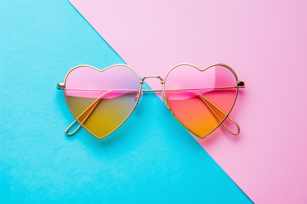 Óculos de sol em forma de coração sobre uma superfície multicolorida