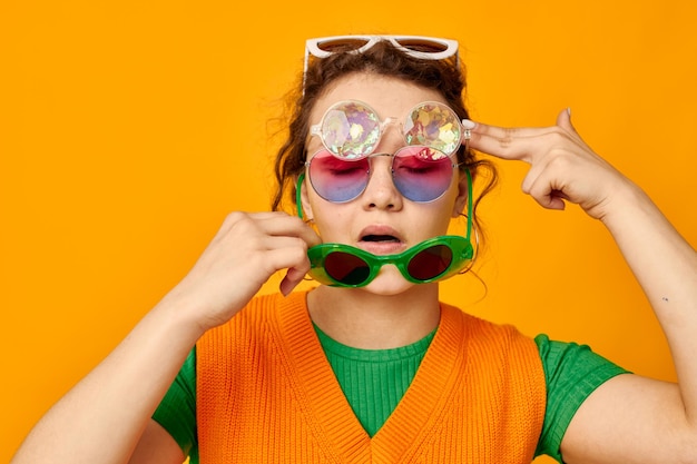 Óculos de sol multicoloridos de mulher bonita no rosto posando fundos isolados de careta inalterados