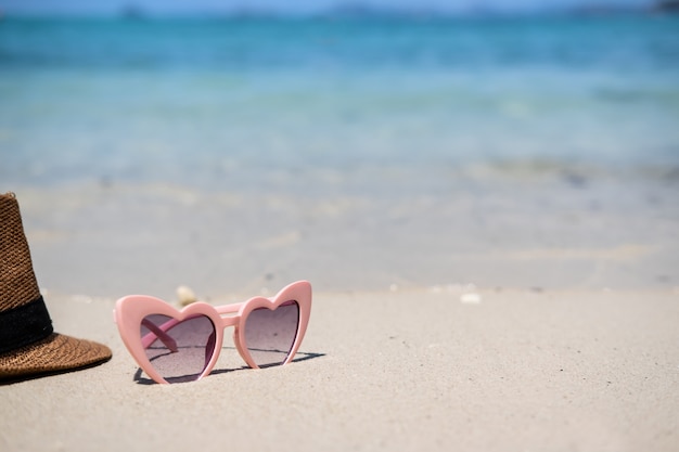 Óculos de sol na praia tropical arenosa branca, férias de verão e conceito de viagem