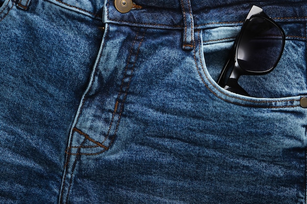 Óculos de sol no bolso da frente da calça jeans