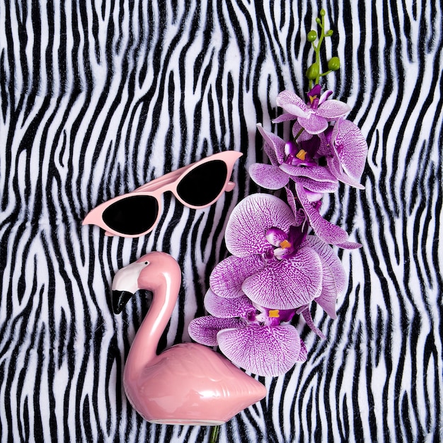 Óculos de sol rosa e flamingo rosa em fundo de impressão de zebra. Vibrações mínimas de praia