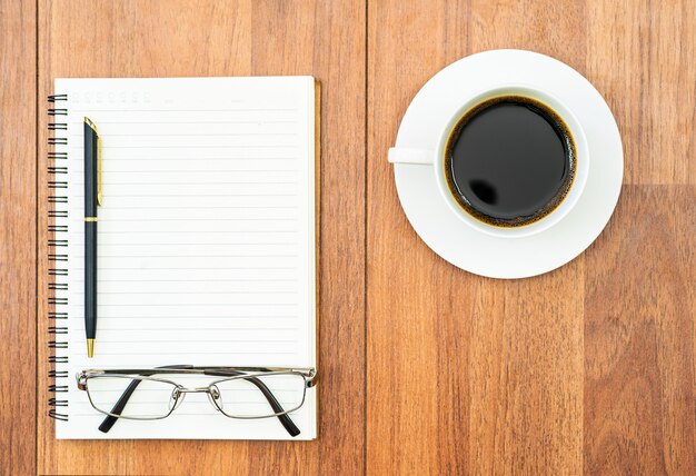 Óculos e bloco de notas com uma xícara de café