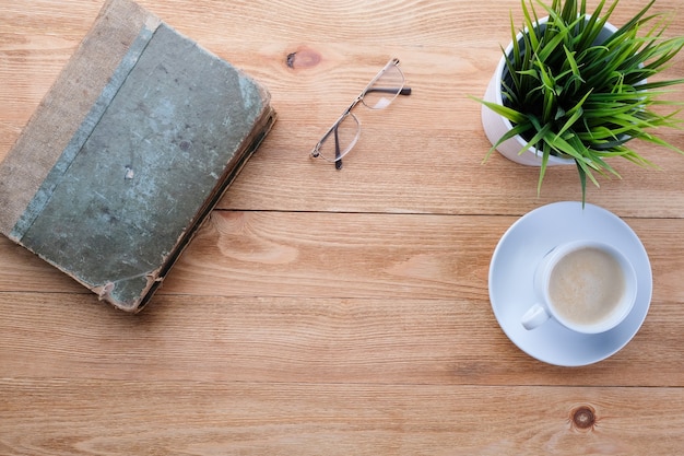 Óculos e um livro antigo em uma mesa de madeira