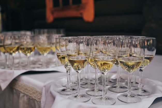 Óculos elegantes com champanhe em pé em uma linha na mesa de servir durante a festa