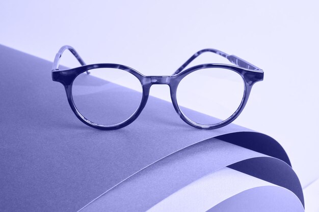 Óculos em papel enrolado, fundo geométrico, tendência de cor muito peri 2022, conceito de teste de visão, acessórios de moda lindos e elegantes em loja de ótica