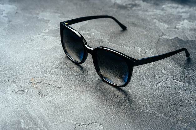 Óculos escuros masculinos na superfície de concreto cinza close-up