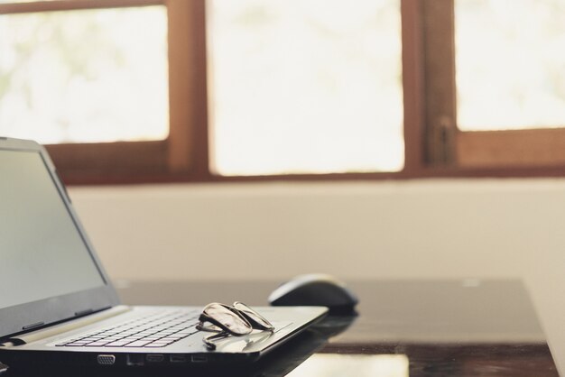 Óculos na mesa de trabalho com gráfico e laptop no local de trabalho de negócios.