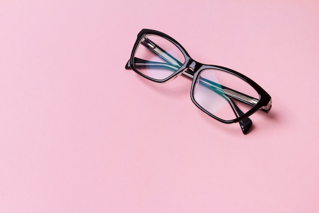 Óculos na moda elegantes na mesa-de-rosa criativa.