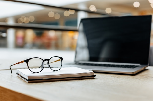 Óculos no local de trabalho no escritório perto do laptop e do bloco de notas