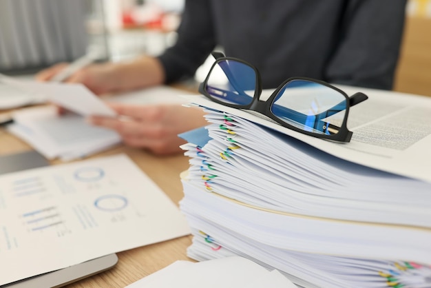 Óculos para visão estão na pilha de documentos no local de trabalho em estudos de mulheres de escritório