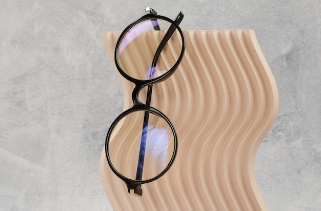 Óculos redondos elegantes para visão em um pódio bege ondulado