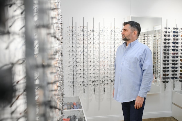 Óculos verificam visão sênior e homem idoso em uma clínica de optometria de consultoria para bem-estar Sorriso feliz e rosto velho com armação de lente e escolha de óculos em uma loja para obter ajuda para obter uma receita