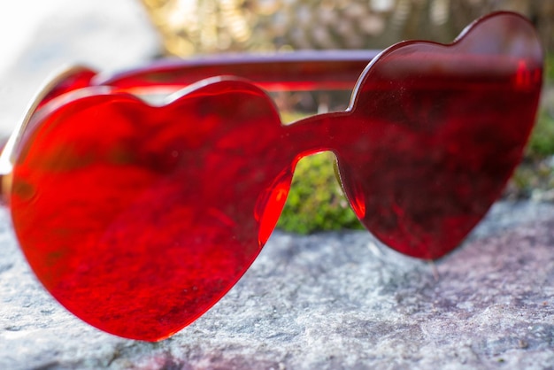Óculos vermelhos em forma de coração em um fundo natural
