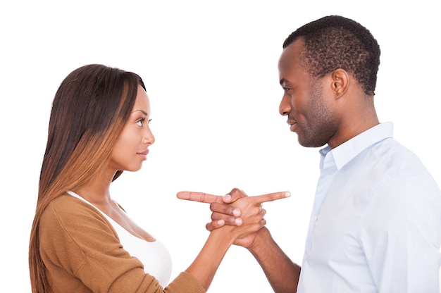 Foto culpar um ao outro. lindo casal jovem africano apontando um para o outro em pé, isolado no fundo branco