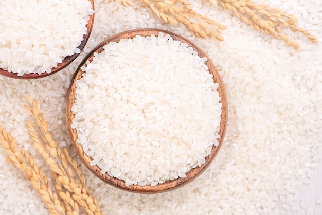 Cultivo de arroz comestible molido pulido blanco crudo sobre fondo blanco en un tazón marrón, concepto de diseño de agricultura orgánica. Alimentos básicos de Asia, de cerca.