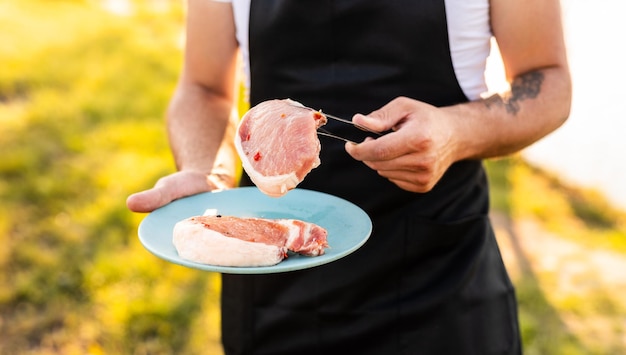 Cultivo de chef masculino con carne cruda en un plato