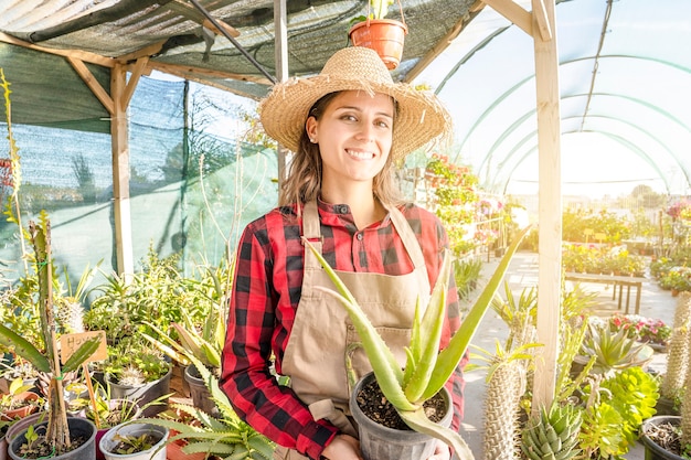 Cultivo de plantas de aloe em uma estufa. jovem profissional sorridente