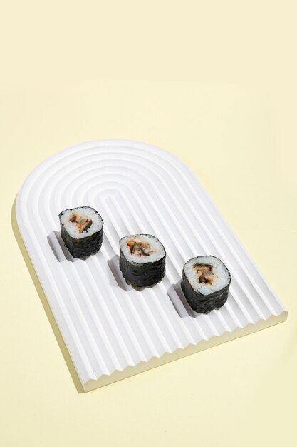 Cultura asiática Rollos de sushi hosomaki japonés con anguila sobre fondo amarillo Cocina oriental culinaria oriental