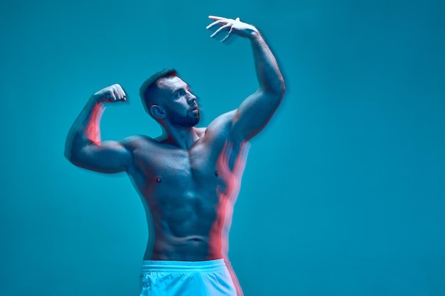 Culturista atlético con torso musculoso desnudo muestra sus músculos abdominales y de brazos largos