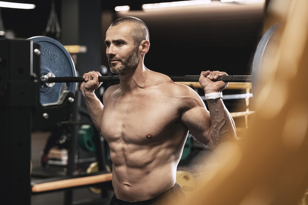 Culturista barbudo guapo durante su entrenamiento con una barra en el gimnasio