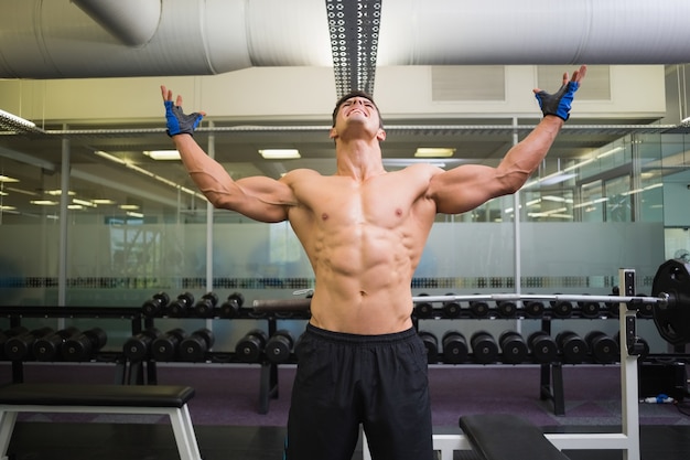 Foto culturista con los brazos levantados en el gimnasio