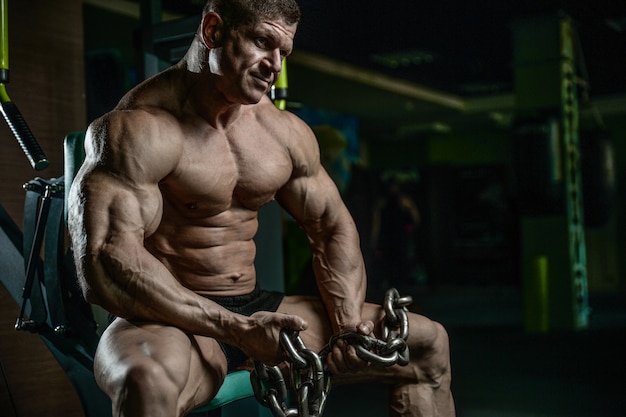 Culturista brutal trabajando en el gimnasio con cadena