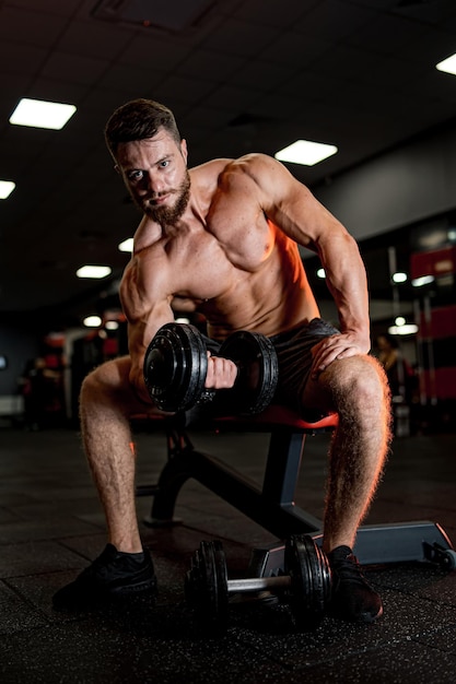 Culturista deportivo haciendo ejercicio en el gimnasio Hombre musculoso fuerte levantando pesas grandes