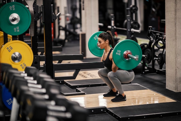 Una culturista femenina fuerte está levantando pesas pesadas en un gimnasio