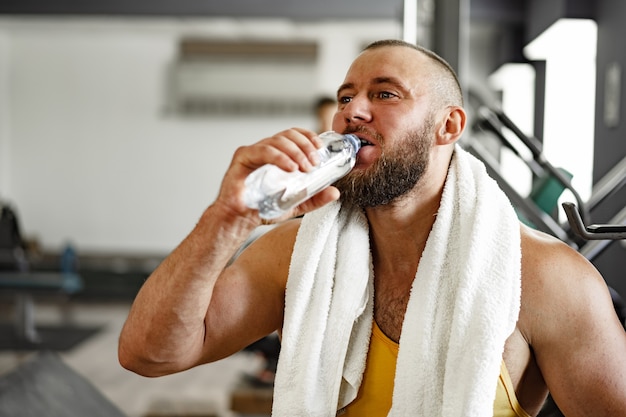 Culturista fuerte con pecho musculoso y hombros en gimnasio