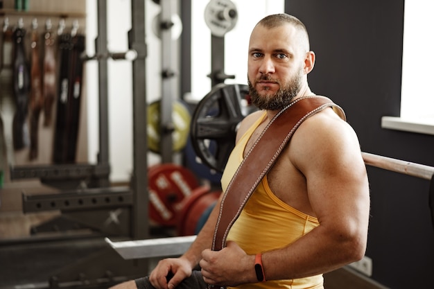 Culturista fuerte con pecho musculoso y hombros en gimnasio