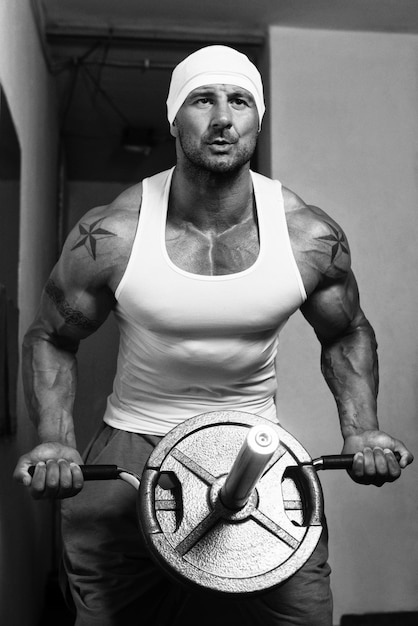 Foto culturista haciendo ejercicio de peso pesado para la espalda con pesas en el gimnasio moderno