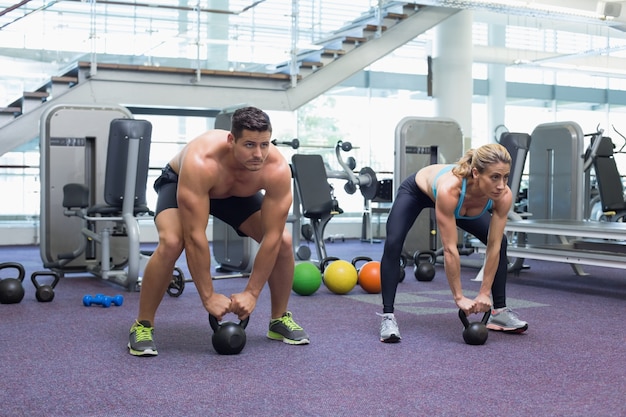 Culturista, hombre y mujer, levantar kettlebells, en, un, squat