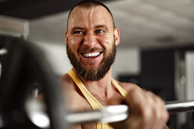 Culturista hombre sonriente alegre de pie en un gimnasio