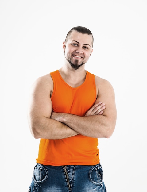 Foto culturista en jeans y camiseta naranja.