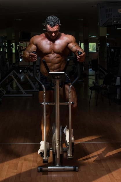 culturista masculino usando la máquina elíptica