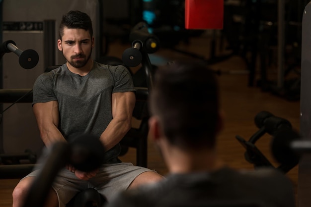 Culturista mostrando sus músculos y posando en el gimnasio