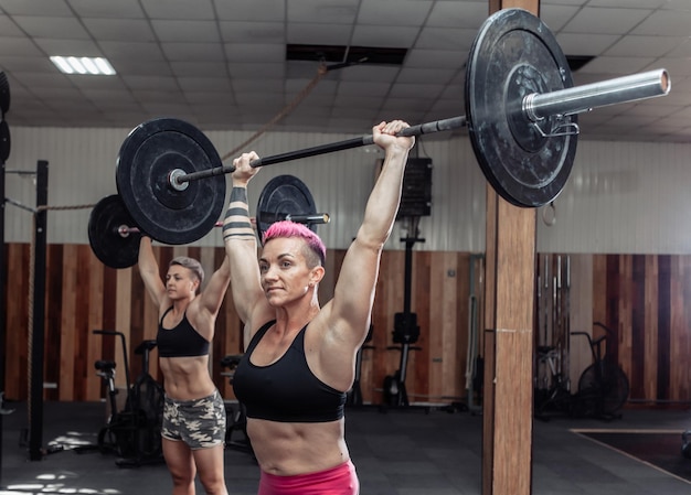 Culturista de mujeres fuertes haciendo sobrecarga con pesas pesadas en el moderno gimnasio cruzado. Clase de entrenamiento funcional. Culturismo y Fitness