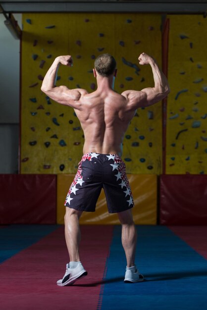 culturista musculoso mostrando su espalda doble bíceps