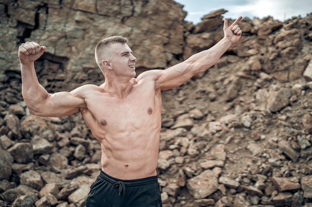 Culturista musculoso con el torso desnudo mostrando sus músculos. Apuesto joven fuerte posando para la cámara.