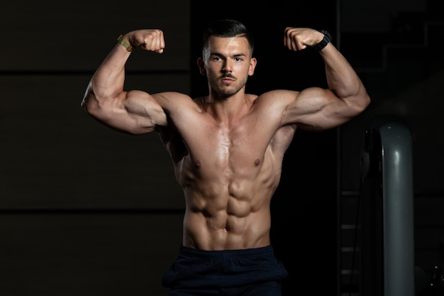 Culturista realizando una pose de doble bíceps frontal en el gimnasio