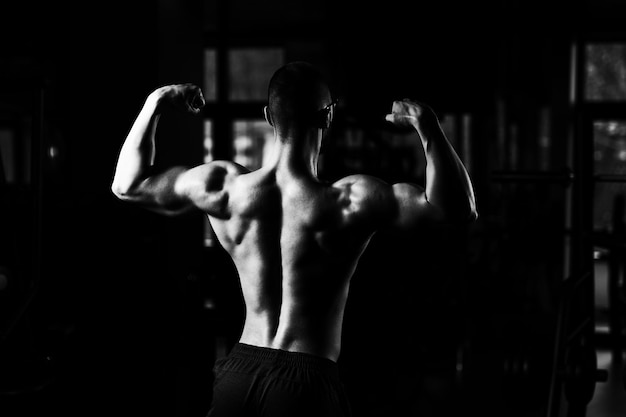 Culturista serio con gafas de pie en el gimnasio