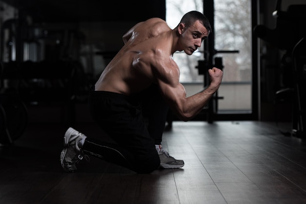 Culturista serio de pie en el gimnasio