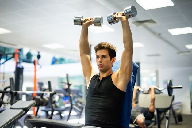 Culturista usando una pesa para hacer ejercicio en un gimnasio