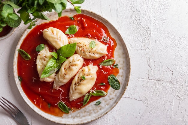 Culurgiones de comida tradicional italiana con salsa de tomate y albahaca